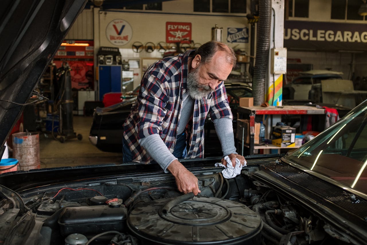 Bearded mechanic working on engine repair in an auto repair shop garage with a focus on hands-on car service.